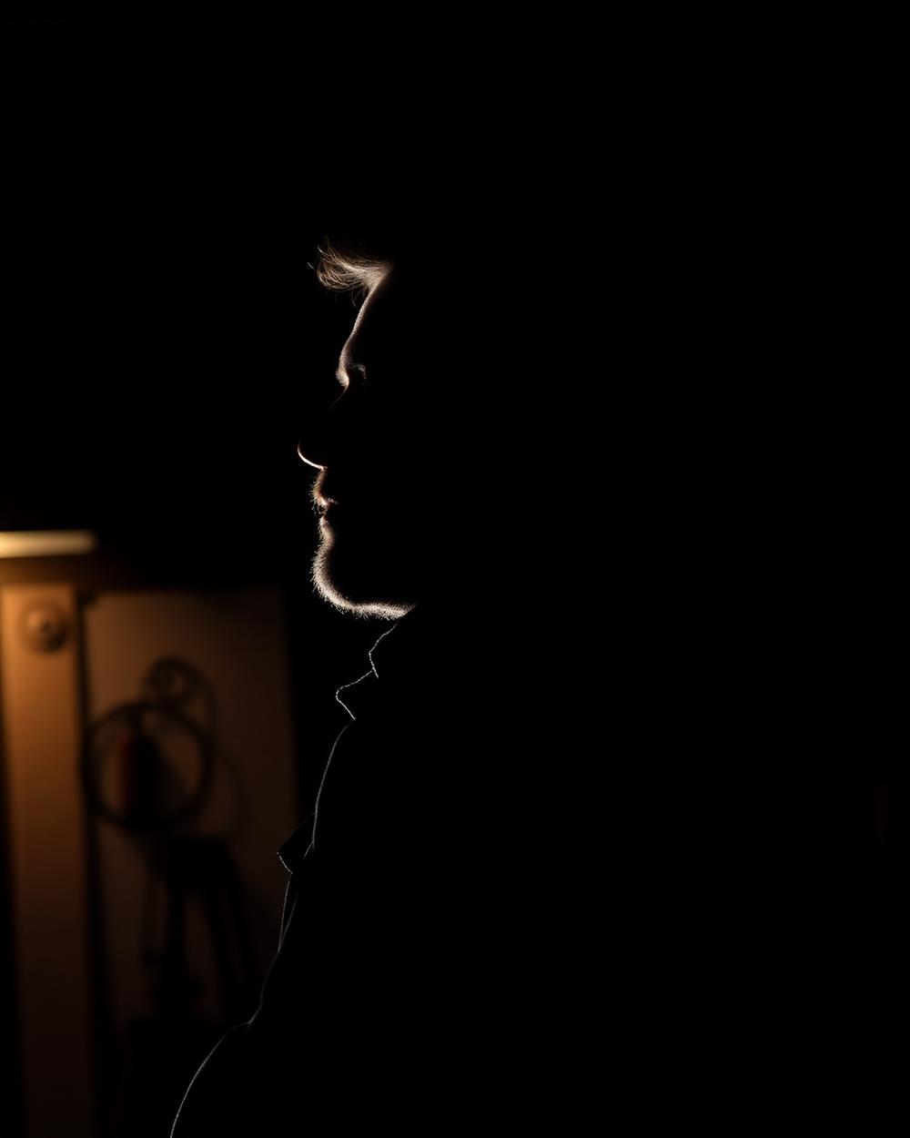 Portrait of a craftsman electrician lit from the side in a workshop